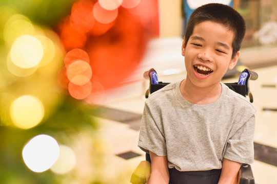 Asian special child on wheelchair smiling as happily with blurred lighting, Christmas Festival background, Life in the education age of disabled children, Happy disabled kid concept.