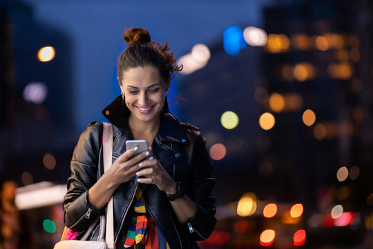 Young woman with smartphone at night in a urban city area
