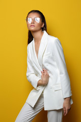 Elegant young woman in glasses on a yellow background