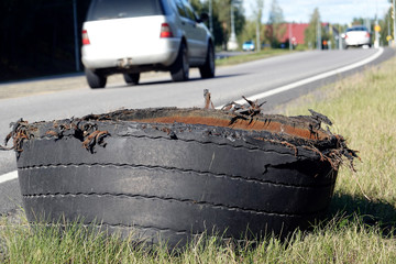 Exploded tire of semi truck on highway roadside. 