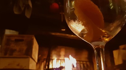 Close up of a glass of wine containing an orange peel, with a fireplace in the background, Vittorio Veneto, Italy