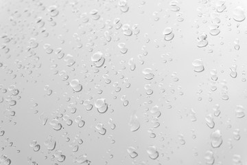 Water drops on glass white gray background.