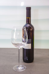 a n empty glass for red wine with a bottle of blue Portuguese red wine behind