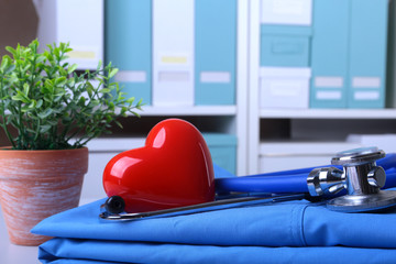 Doctor coat with medical stethoscope and red heart on the desk