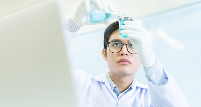 close up asian scientist man wear protective glove hold test tube flask and  blending scientific liquid solution to beaker at laboratory room for research and development about medical and healthcare - Powered by Adobe