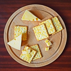 Fresh crispy cracker with cheese and sesame on wooden background.
