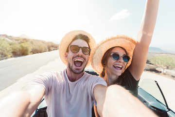 Happy couple in love taking a selfie when road trip in a convertible car