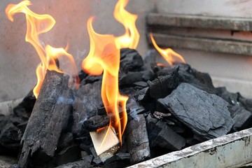 close up of flames between the charcoals in the barbecue grill