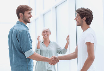 colleagues shaking hands in the office lobby
