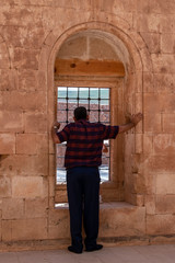 Fototapeta na wymiar Dogubayazıt, Turkey: a man from behind in front of a window in a courtyard of the Ishak Pasha Palace, semi-ruined palace of Ottoman period (1685-1784), example of surviving historical Turkish palace
