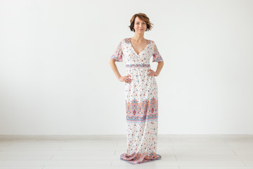 people, fashion and style concept - young woman posing in clothes in studio on white background