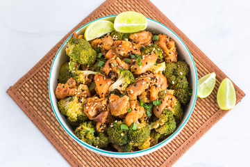 Broccoli and Chicken Stir Fry in a Bowl with Lemon, White Background Top View Photo.