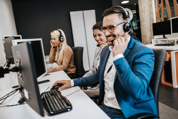 Handsome male customer service agent with headset working in call center.