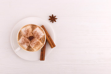 Cup of coffee with marshmallows and cocoa, cinnamon and star anise, on a white background.