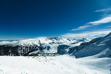 Fototapeta na wymiar Snowy ski slopes and chair ski lifts station in mountain ski resort.