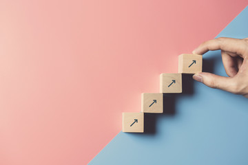Business concept growth success process, Close up man hand arranging wood block stacking as step stair on paper blue and pink background, copy space. - obrazy, fototapety, plakaty
