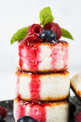 Small cottage cheese pancakes with berries on a white background.