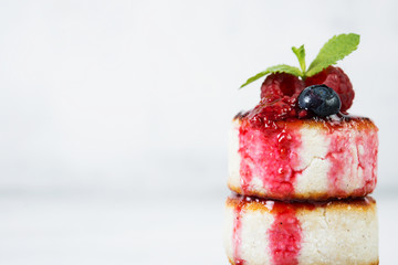 Small cottage cheese pancakes with berries on a white background.