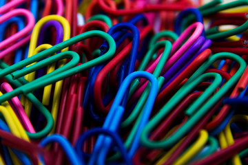 A colorful paper clip background. A variety of scattered colorful plastic paperclips