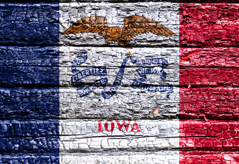 The national flag of the US state Iowa in against a black charred wooden wall on the day of independence. Political and religious disputes, fire department and firefighters.