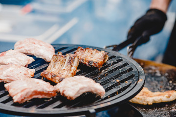 Pork ribs and steak cooked on grill, open fire street food festival