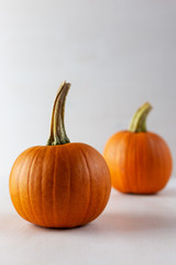 Ripe orange pumpkins on a light background. Vertical photo.