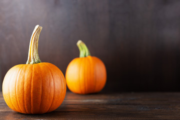 Ripe orange pumpkins on a dark wooden background with copy space.
