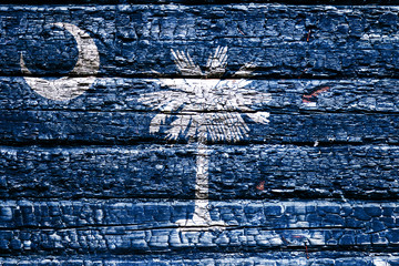 The national flag of the US state South Carolina in against a black charred wooden wall on the day of independence. Political and religious disputes, fire department and firefighters.