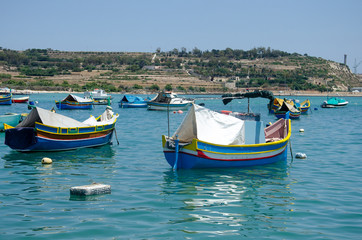 Fototapeta na wymiar Colored fishing Luzzu boats in Marsaxlokk harbor, Malta