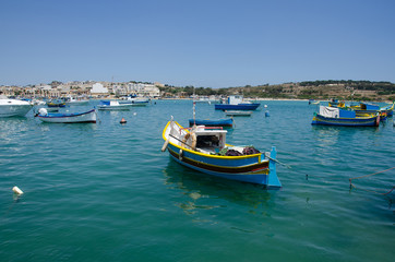 Colorful painted wood boats with the typical protective eyes on a sunny day in Marsaxlokk, Malta.