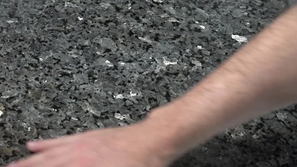 Male hand cleaning granite kitchen countertop with a wet towel