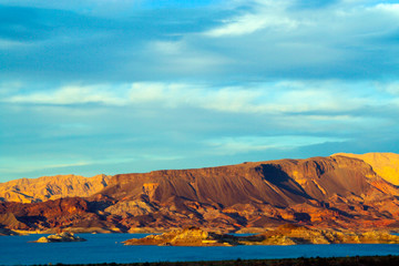 Fototapeta na wymiar View over blue lake water on dry barren mountains in evening sunlight - Lake Powell, USA