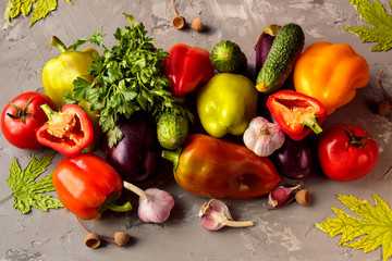 Autumn vegetables (pepper, eggplant, tomatoes, garlik, cucumbers) in a wooden box on a wooden table. Decorated with acorns and dry maple leaves The concept of healthy and diet food.