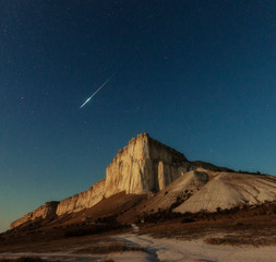 Night star sky and meteor over rock