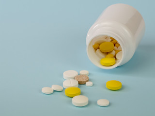 Several tablets fall out of the plastic jar on the surface. Background image on medical and pharmaceutical topics