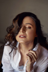 Obraz premium Classic beauty portrait of young woman with blue eyes and dark hair, weared in white shirt and black trousers.Studio shot