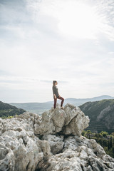 A girl in solitude stands on top of a hill and she is happy.