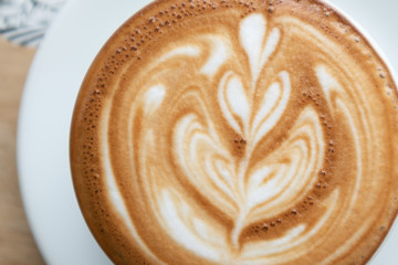 Coffee cup latte art in heart shape with a cup of dark coffee and dark chocolate on wooden table.Frothy drink for coffee break after working or weekend meeting