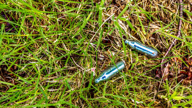 Empty bulbs of nitrous oxide or laughing gas on the grass in a public park, hippie crack is used as a recreational drug or as a party drug