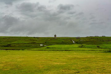 Obraz premium Beautiful landscape of the Irish countryside with the castle Doonagore in the background in the village of Doolin, Wild Atlantic Way, cloudy day in county Clare in Ireland