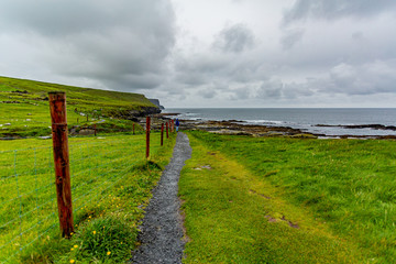 Beautiful landscape of the coast and a rural footpath in of the coastal route walk from Doolin to the Cliffs of Moher, geosites and geopark, Wild Atlantic Way, cloudy day in county Clare in Ireland