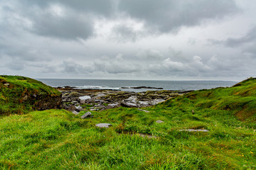 View of the sea and the coast with limestone rocks along the coastal walk route from Doolin to the Cliffs of Moher, geosites and geopark, Wild Atlantic Way, rainy day in county Clare in Ireland