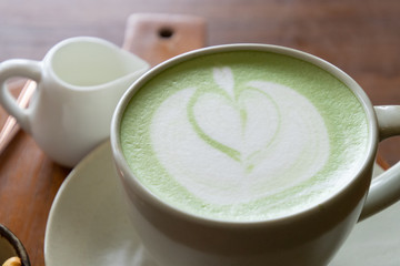 Coffee cup with Green Matcha latte art foam on wood table in coffee shop with copy space.Coffee is one of the most popular beverages.Improve Energy Levels and Burn Fat
