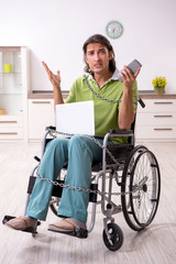 Young male invalid in wheel-chair suffering at home