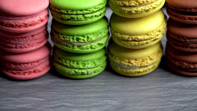 multi-colored macaroons on a gray countertop on a dark background. Tasty traditional dessert.