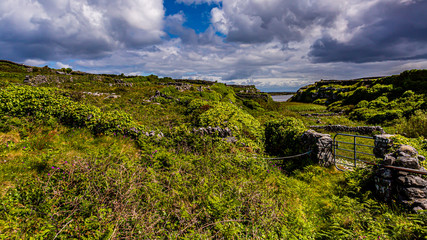 Fototapeta na wymiar Beautiful view of the Irish countryside between stone fences on the Inis Oirr island with the sea in the background, wonderful day on the Inisheer island in the west of the coast of Ireland