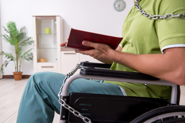 Young male invalid in wheel-chair suffering at home