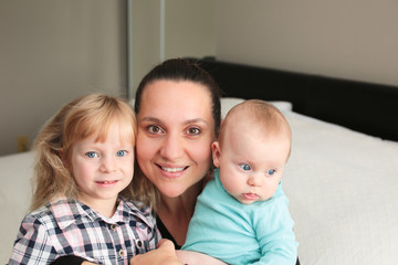 Close up portrait of Young Beautiful Mother with two daughters, Cute 6 Month Old Baby Girl , 7 Years Old Girl, Happy Family, Happy Mother’s Day, Best Mother Concept, The Most Beautiful Girls in the wo