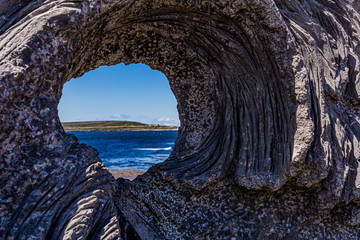 Beautiful view of the sea seen through a hole in a rock with a rough texture on the island of Inis...