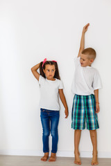 Obraz premium Little boy and girl measuring their height isolated on white background